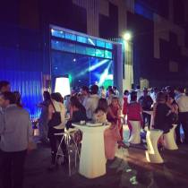 Asistentes sentados junto a la mesa del DJ durante un evento corporativo