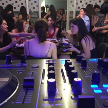 Evento privado con invitados disfrutando del banquete mientras suena la música desde la mesa de DJ